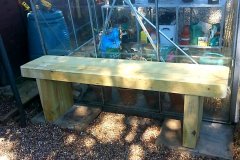Garden bench next to greenhouse